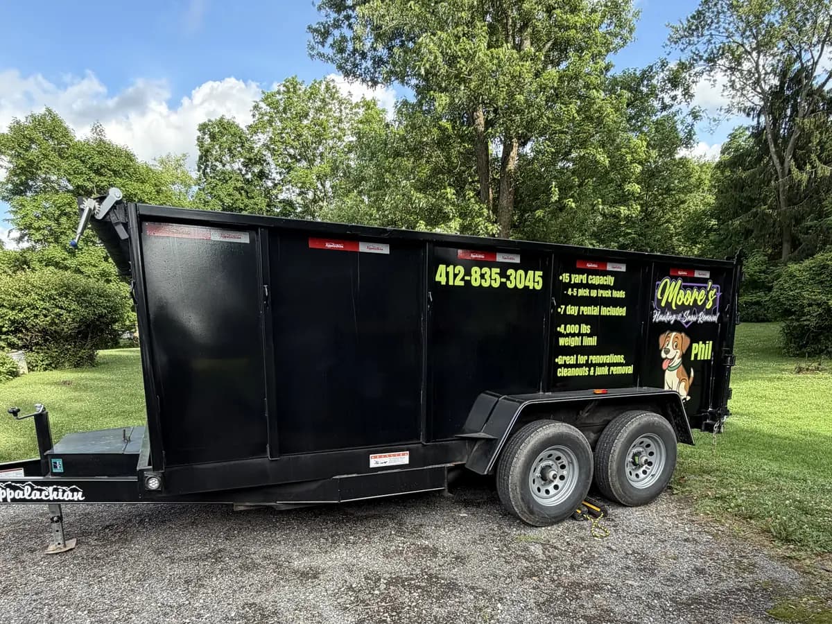 Moore's 15-yard dump trailer with capacity decals and Phil the dog